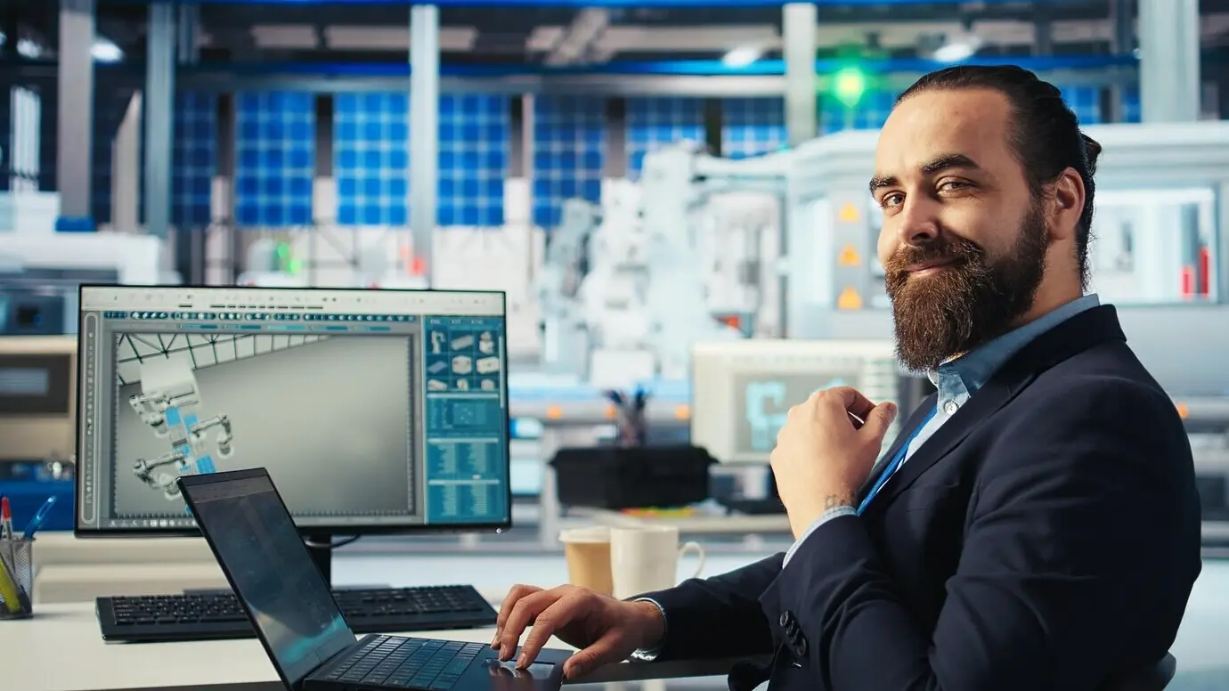 Ein Spezialist inspiziert mit einem Laptop die Anlage, die Solarzellen auf Förderbänder legt.